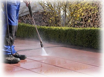 A person using a power washer on the ground.