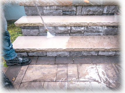 A person cleaning steps with a power washer.